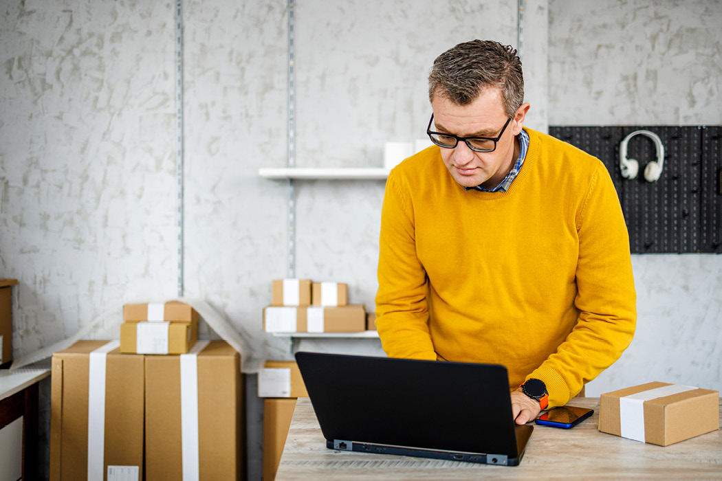 Man working on a laptop with boxes behind him