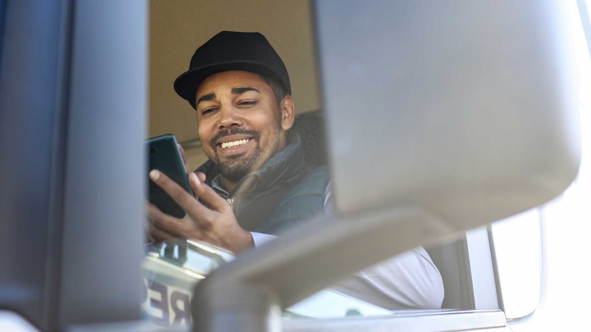 Man in his truck cab looking at an app on his mobile phone