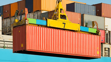 Container being loaded onto container ship depicting importance of trade policy consulting