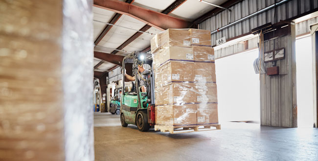 Forklift transporting boxes wrapped in clear plastic.